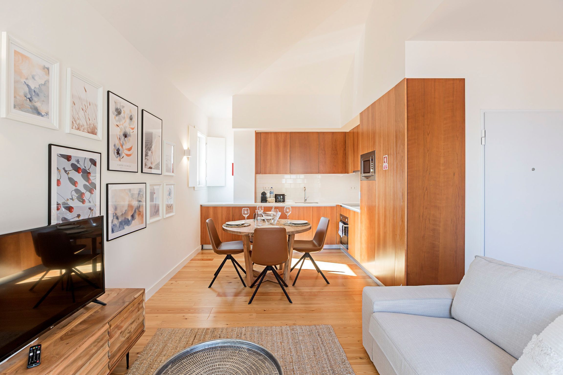 Un salon moderne doté d’un téléviseur à écran plat, d’un canapé et d’un coin repas avec une table ronde et des chaises.