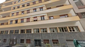A multi-story building with balconies, large windows, and a ground-level entrance. - Le Petit Bijou (Rome)