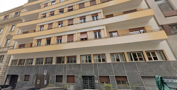 Um edifício com várias andares, varandas, janelas amplas e entrada no nível da rua.