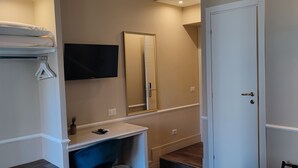A bathroom with a mirror, a sink, a towel rack, and a wall-mounted TV. - Le Petit Bijou (Rome)