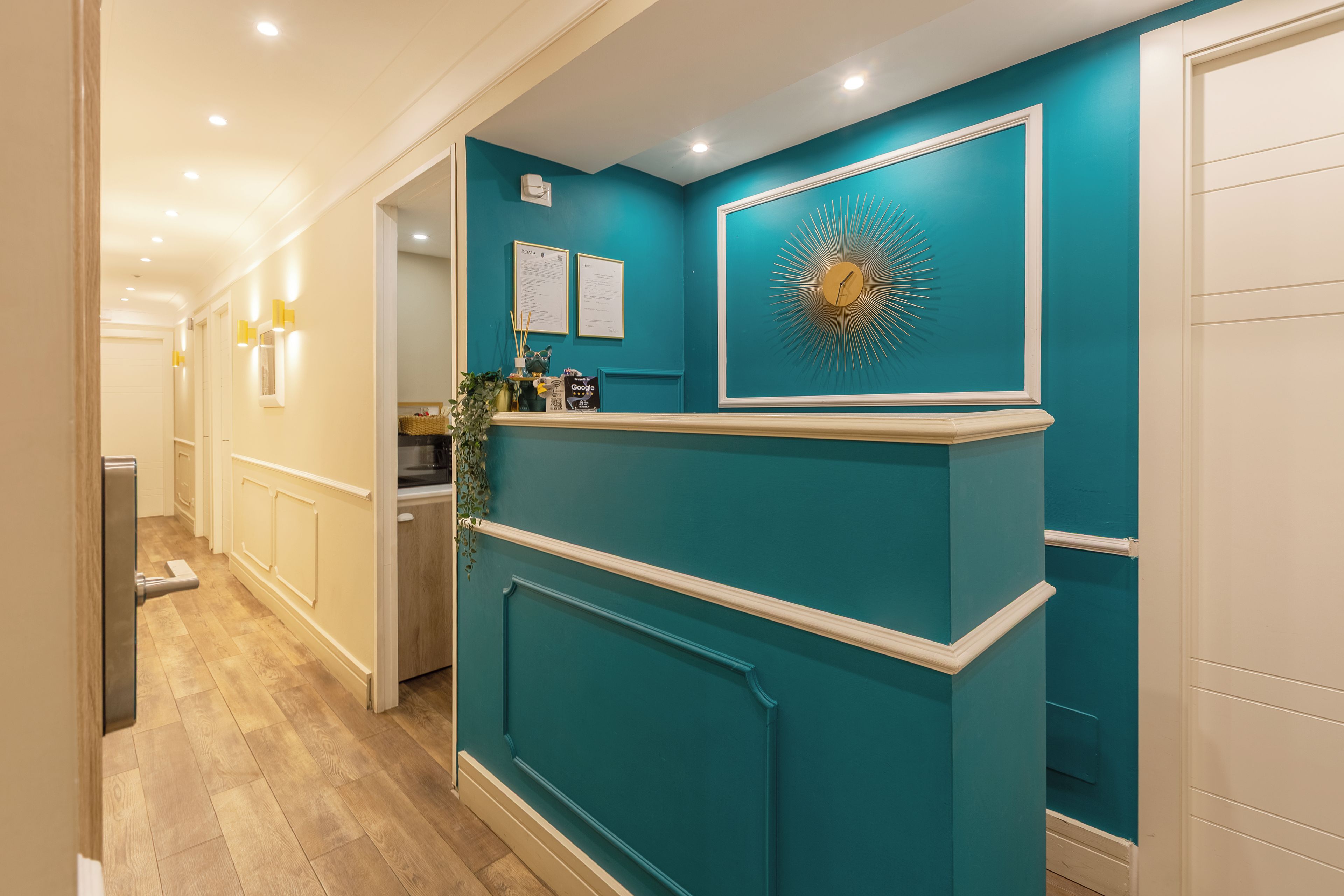 A hallway with a reception desk, a wall-mounted clock, and framed notices.