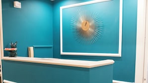 A reception desk with a teal color scheme and a decorative wall clock. - Le Petit Bijou (Rome)