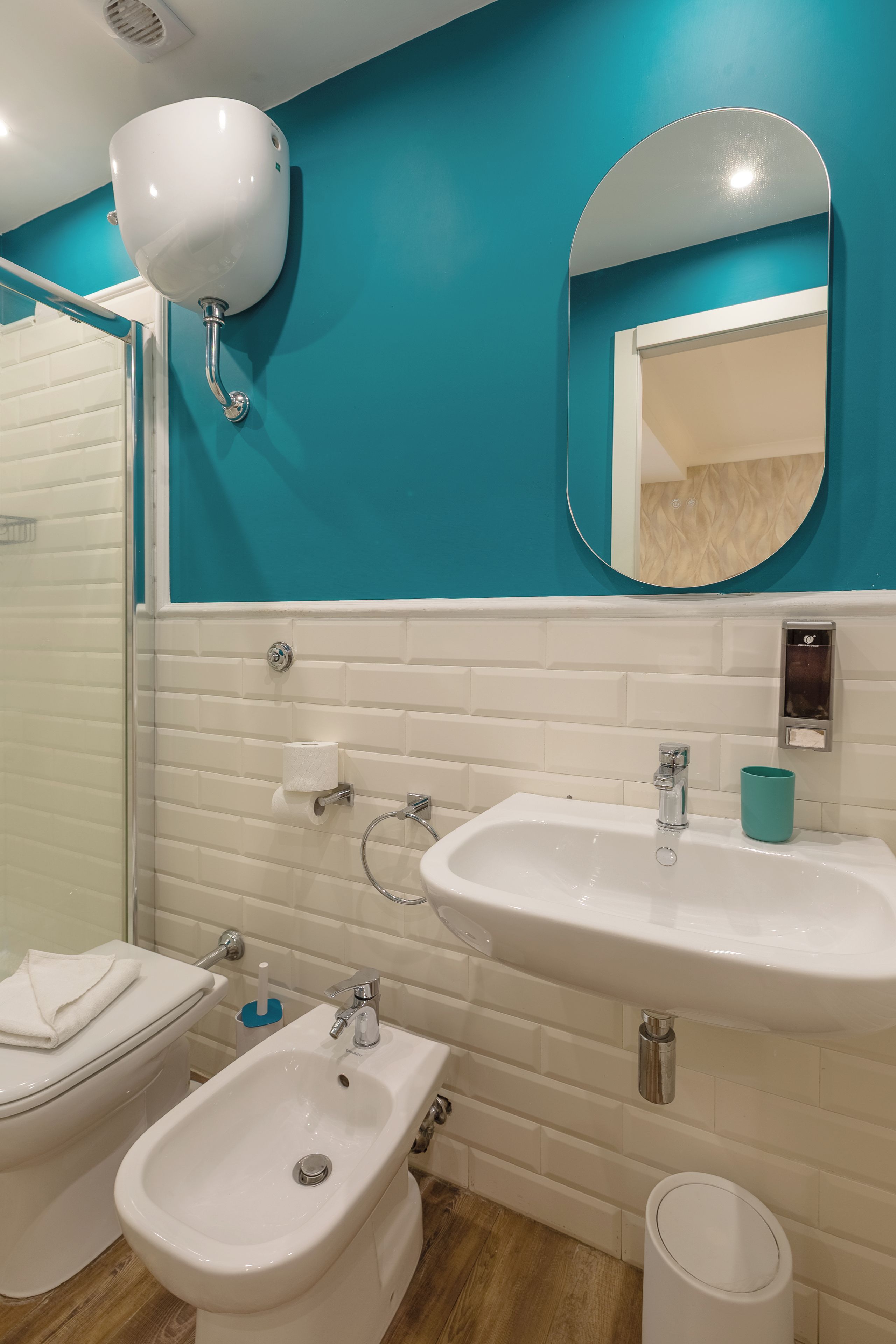 A bathroom with a toilet, bidet, sink, and mirror.