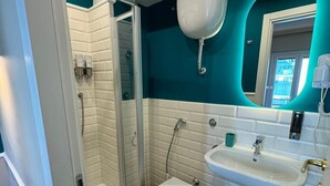 A modern bathroom with a glass-enclosed shower, a white toilet, and a sink with a mirror. - Le Petit Bijou (Rome)