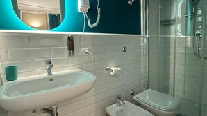 A modern bathroom with a large mirror, two sinks, a bidet, a toilet, and a glass-enclosed shower. - Le Petit Bijou (Rome)