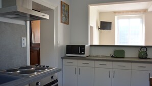 A compact kitchen with a stove, microwave, and a small window.