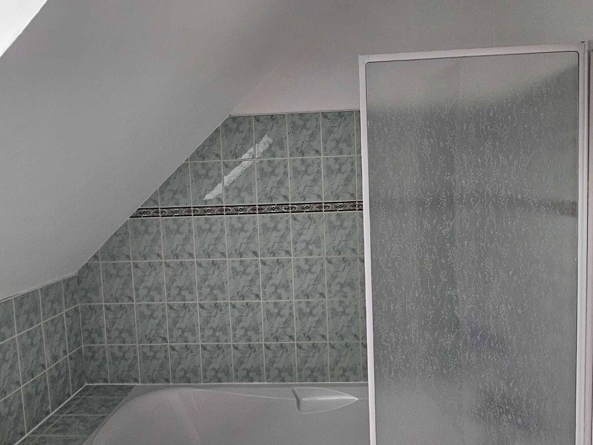 A bathroom with green marble tiles, a shower area, and a bathtub.