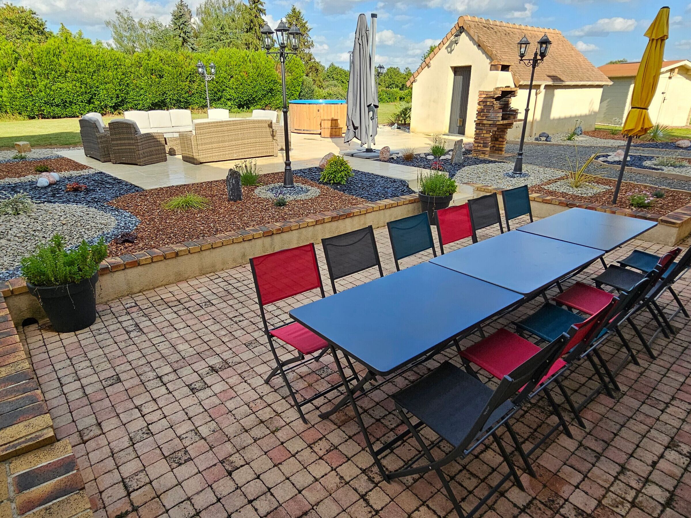 Une terrasse extérieure avec une table et des chaises, un jacuzzi et un petit bâtiment.