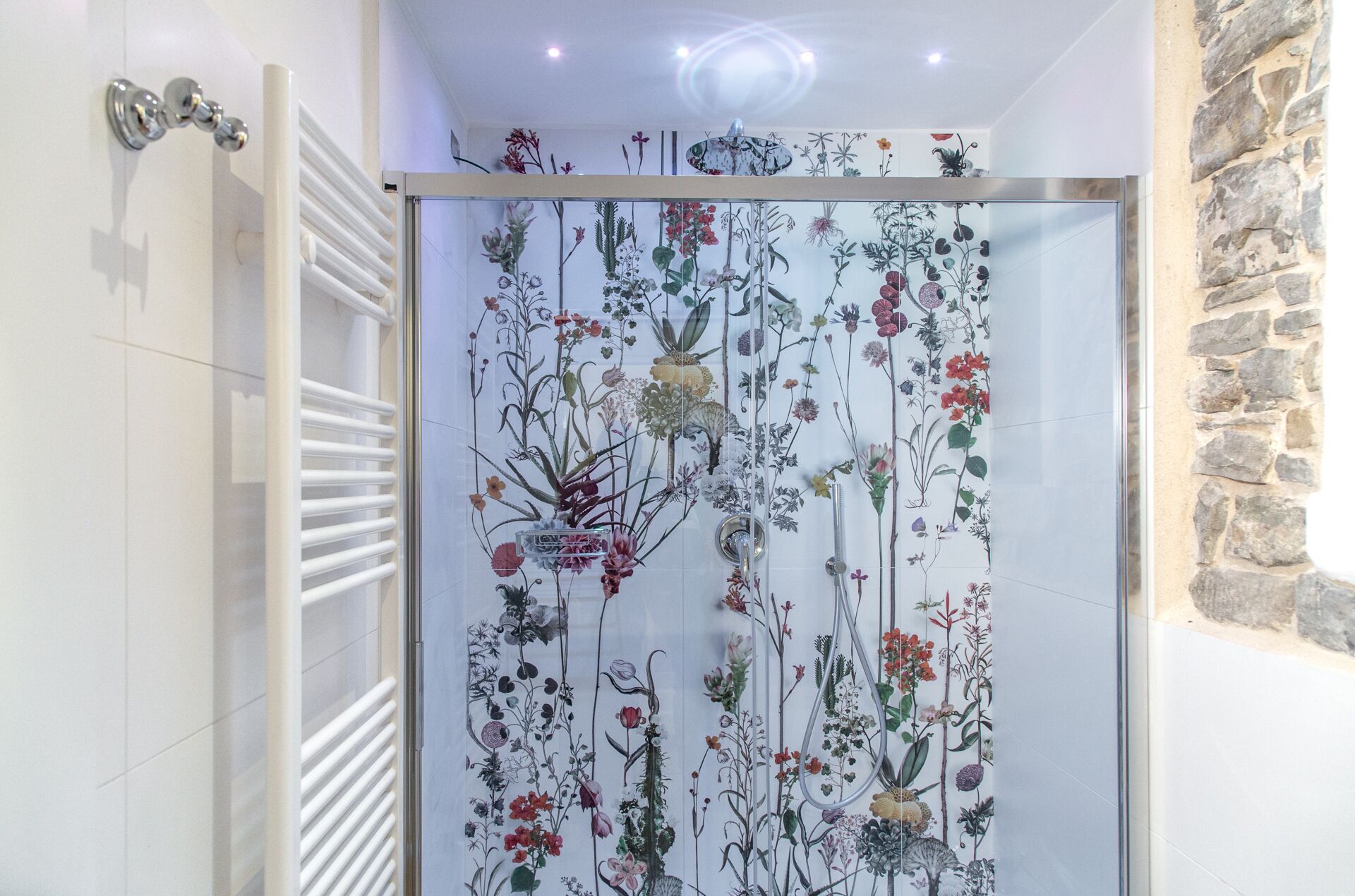 Un bagno con box doccia in vetro decorato con un motivo floreale.