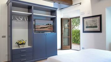 A bedroom with a bed, a wardrobe, a painting, and a view of greenery.