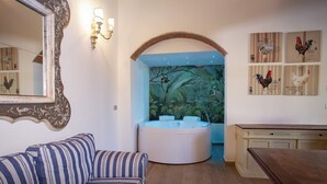 Een kamer met een rond ligbad, een gestreept bankje en wanddecoratie.