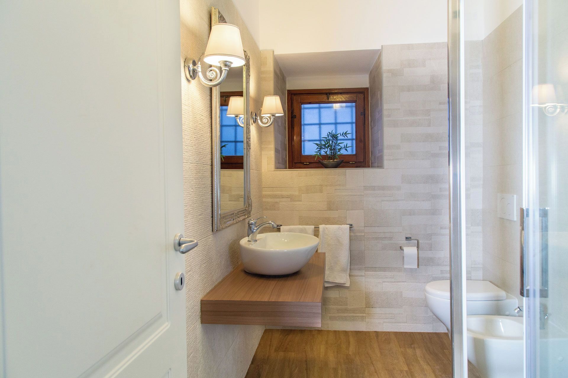 Un baño moderno con un espejo grande, un lavamanos, una ventana y una zona de ducha.