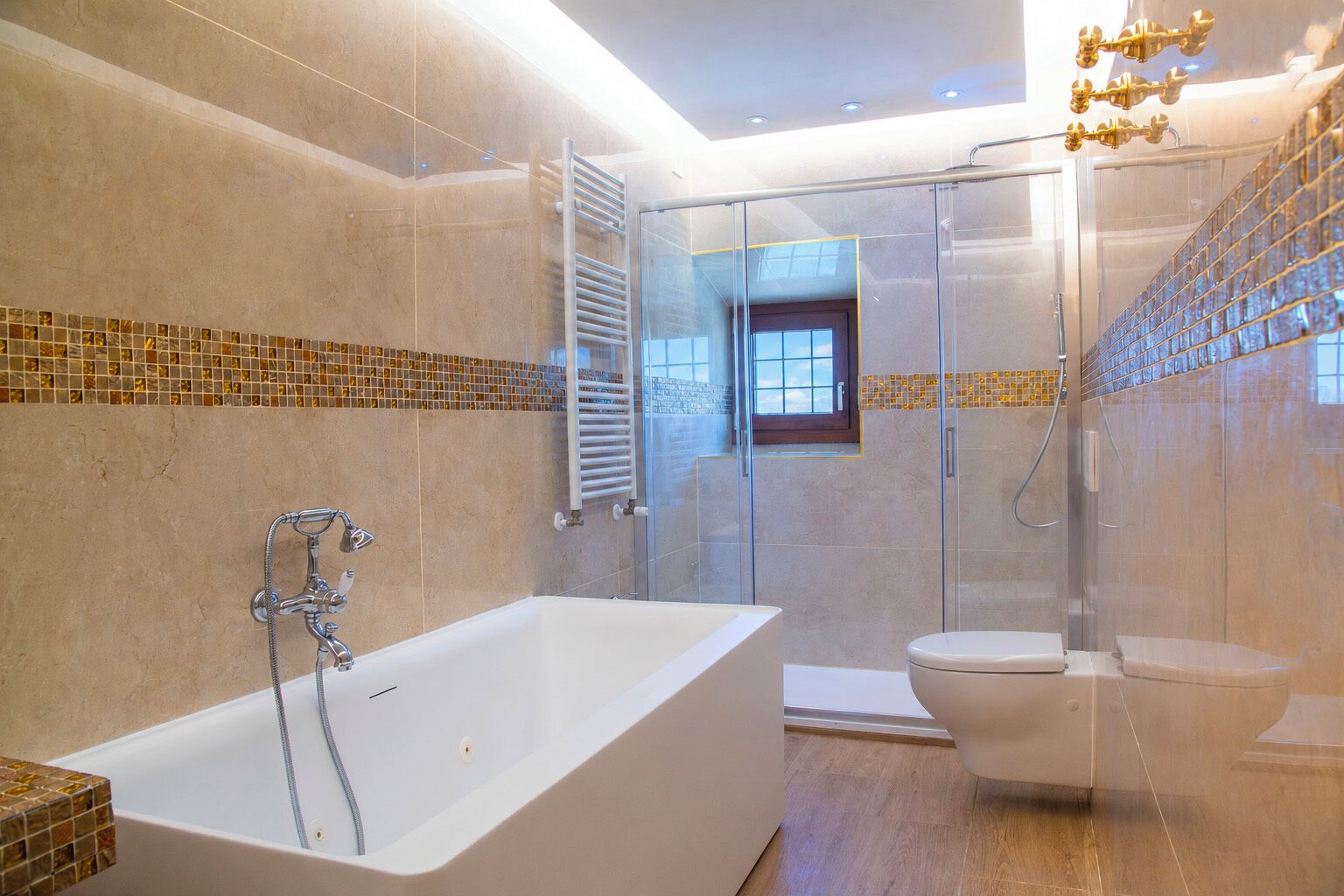 A modern bathroom with a bathtub, toilet, and glass-enclosed shower area.