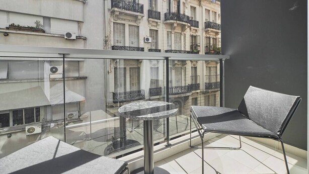 A balcony with a glass railing, a round table, and two chairs. - NoMa Work & Travel - 2A (Centro)