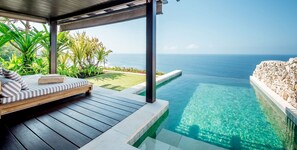 Un terrazzo in legno con area relax e piscina cristallina affacciata sul mare.