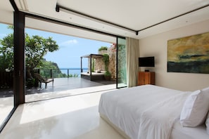 A bedroom with a large bed, a TV, and a view of the ocean. - The Ungasan Clifftop Resort (Pecatu)