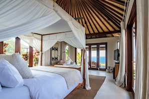 A bedroom with a canopy bed, a television, and a view of the ocean. - The Ungasan Clifftop Resort (Pecatu)