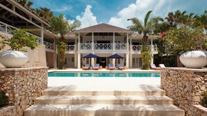 A resort with a swimming pool, stone steps, and lounge chairs. - The Ungasan Clifftop Resort (Pecatu)