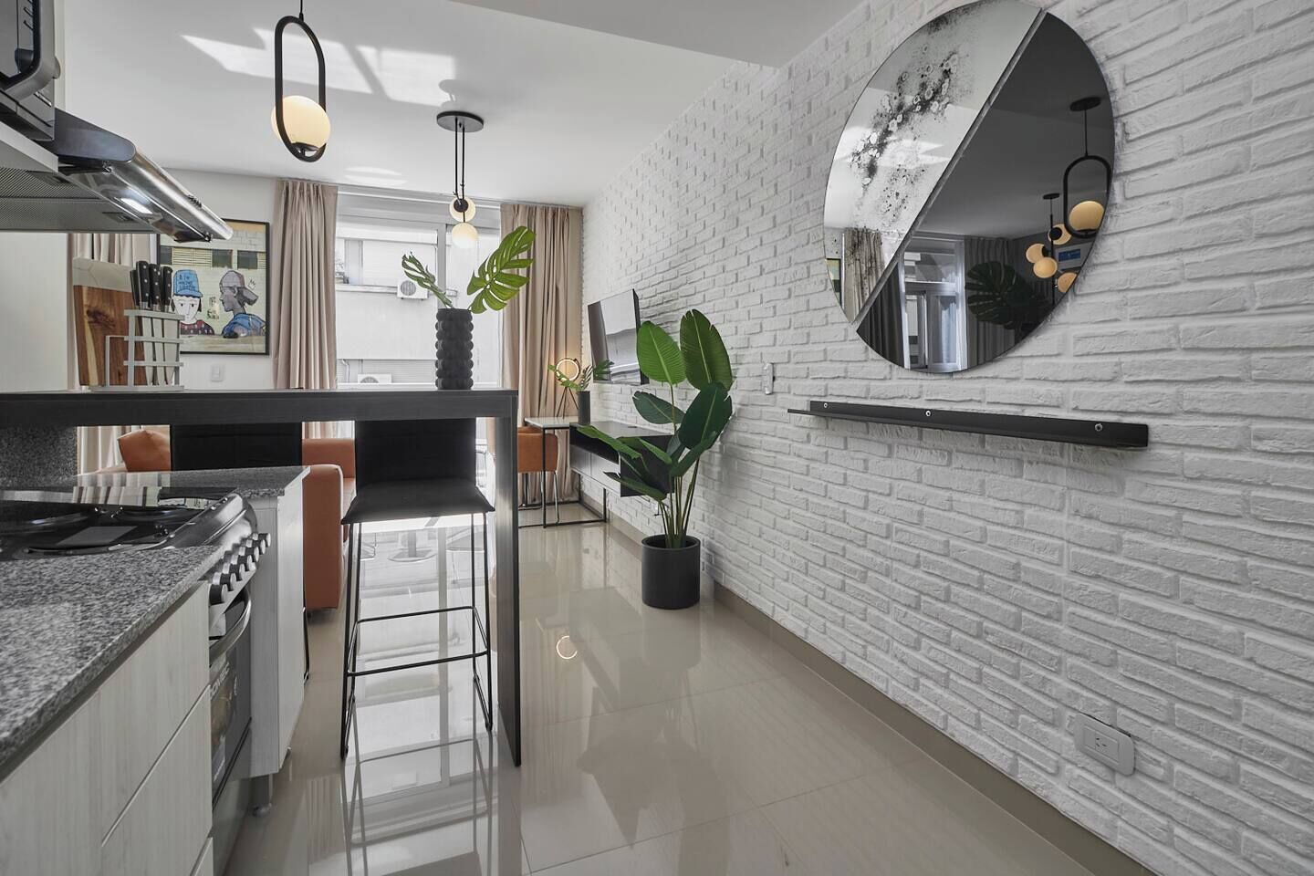 A modern kitchen with a central island, a white brick wall, and a large mirror.