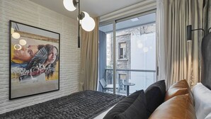 Une pièce moderne dotée d’une grande fenêtre, d’un canapé noir, d’une œuvre d’art encadrée et d’un banc au design original et à la texture particulière.