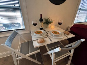 A dining table with two bowls of soup, a bottle of wine, and a candle.