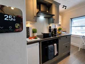 A modern kitchen with a digital thermometer, a stove, and a window with blinds.
