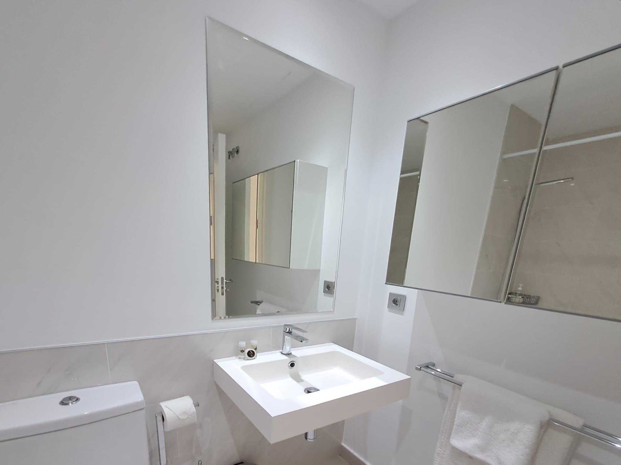 Une salle de bain moderne avec un lavabo blanc, un miroir et des toilettes.