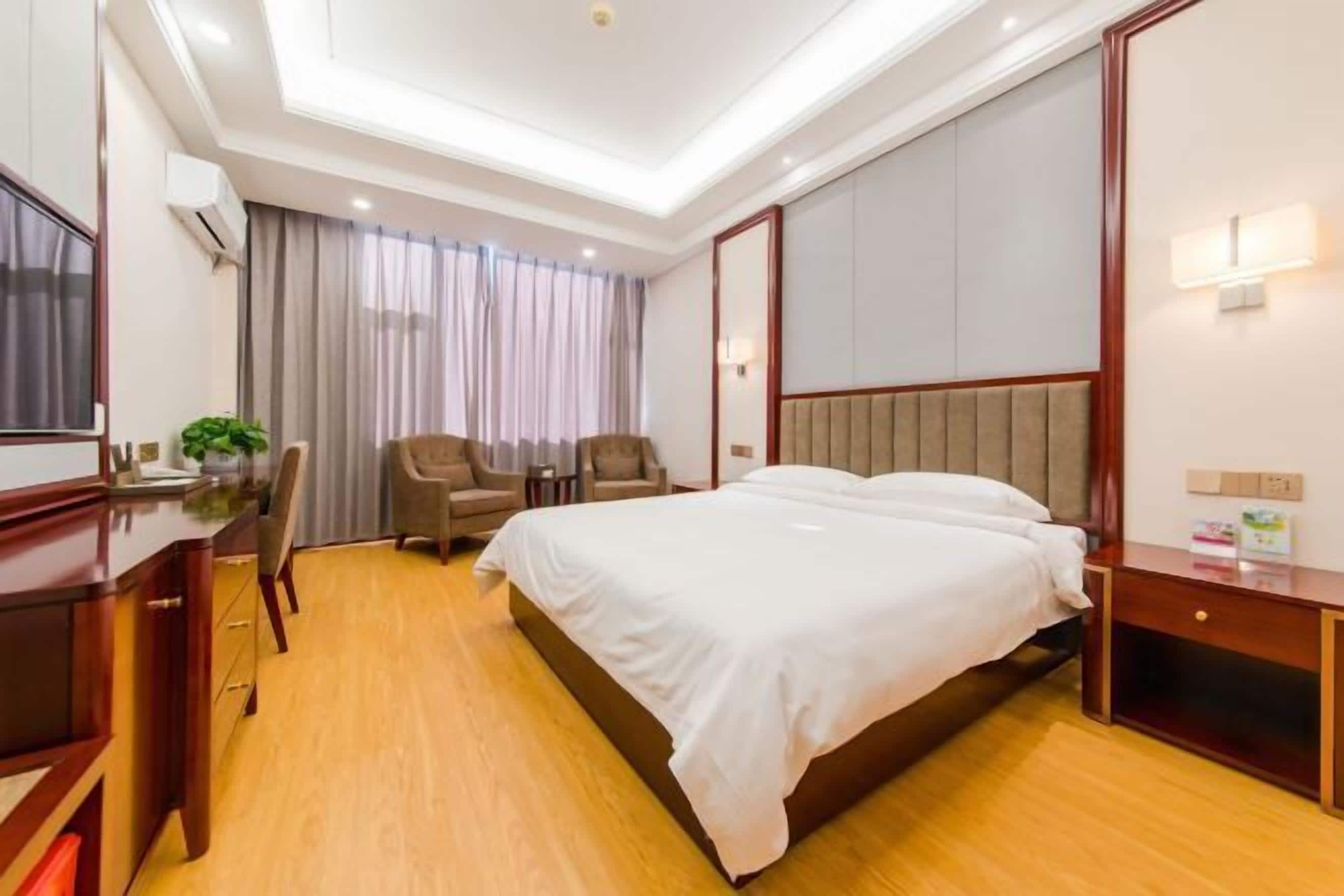 Een hotelkamer met een bed, bureau, stoel en een grote spiegel.