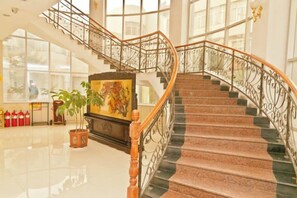 A grand staircase with a wooden handrail and metal balustrade, leading to an upper floor. - Guangrao Hotel (Guangrao)