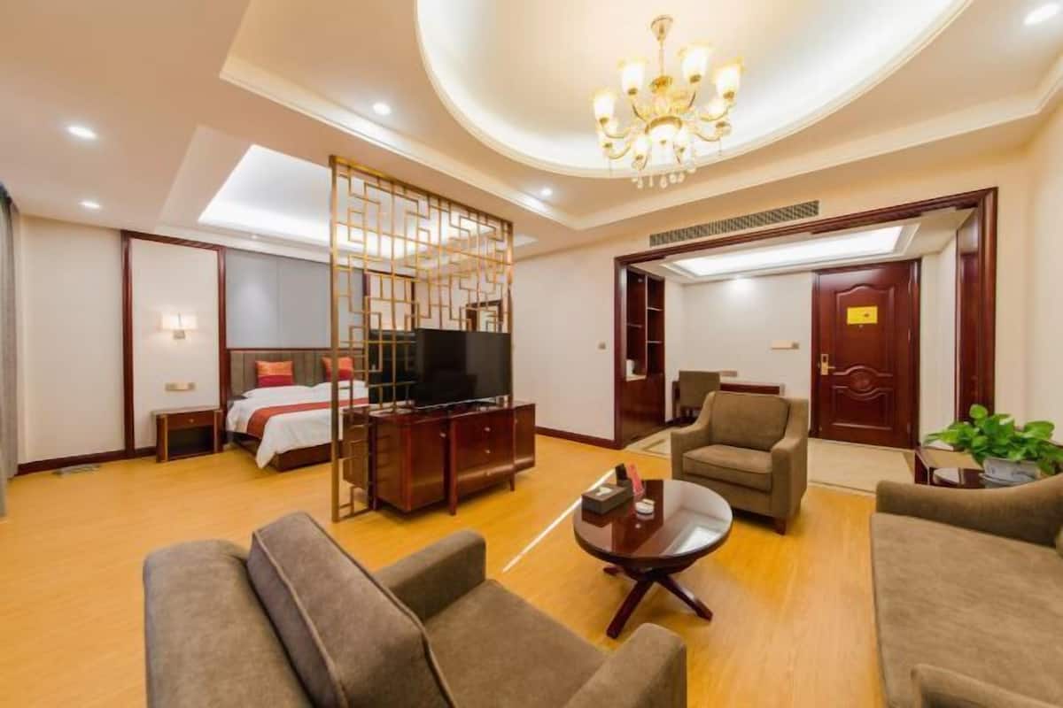 A hotel room with a bed, a TV, a sofa, a coffee table, and a desk with a computer.