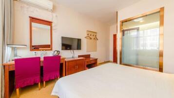 A hotel room with a bed, a desk with a chair, a television, and a window.