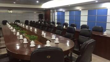 Une salle de conférence avec une longue table, de nombreuses chaises et un mur bleu orné d’un motif quadrillé.