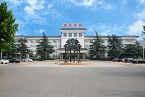 A building with a sign, a parking lot, and trees. - Guangrao Hotel (Guangrao)