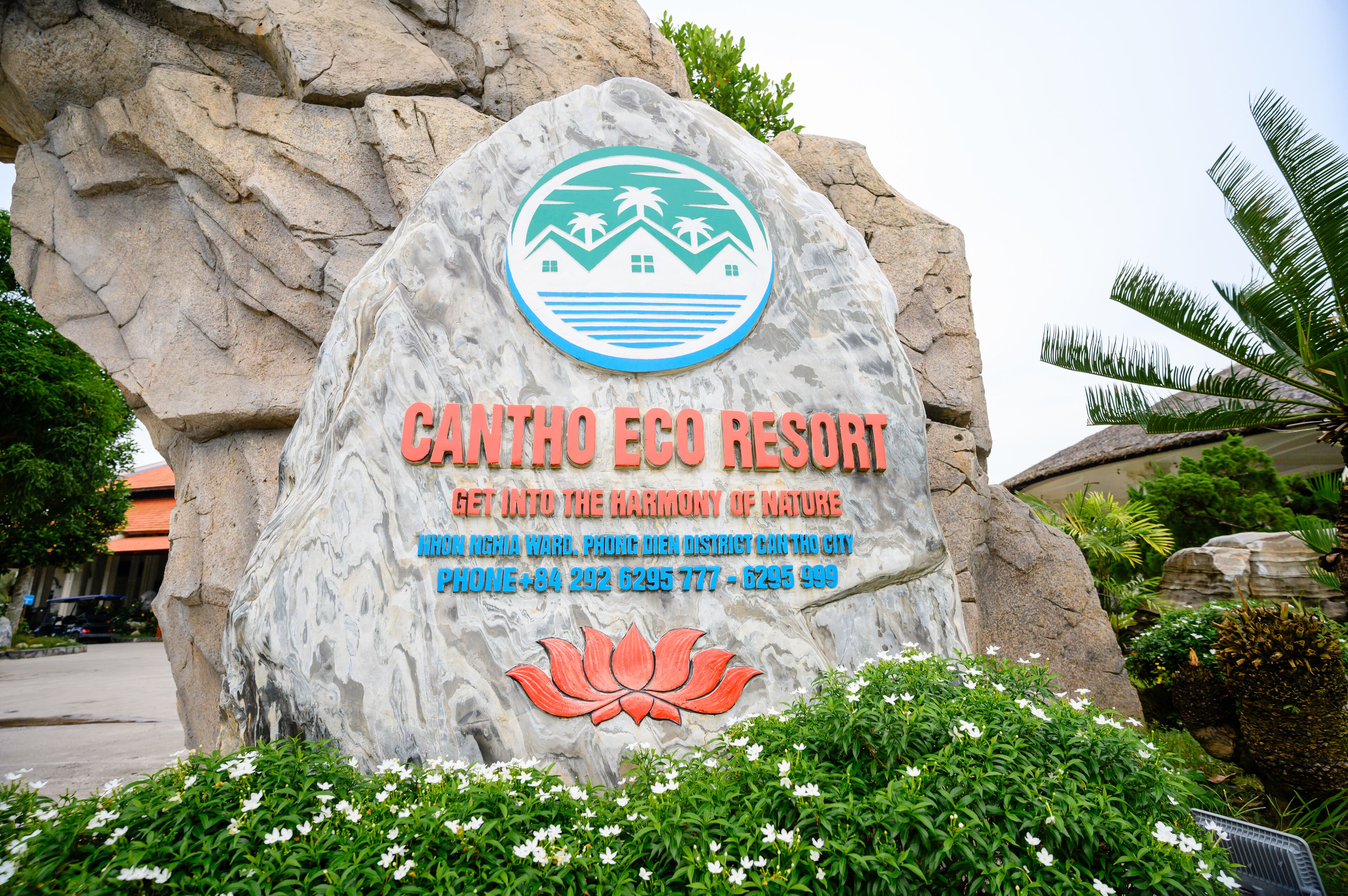 A large rock with a sign for Canttho Eco Resort, featuring a logo, resort name, and contact information.