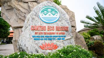 A large rock with a sign for Canttho Eco Resort, featuring a logo, resort name, and contact information.