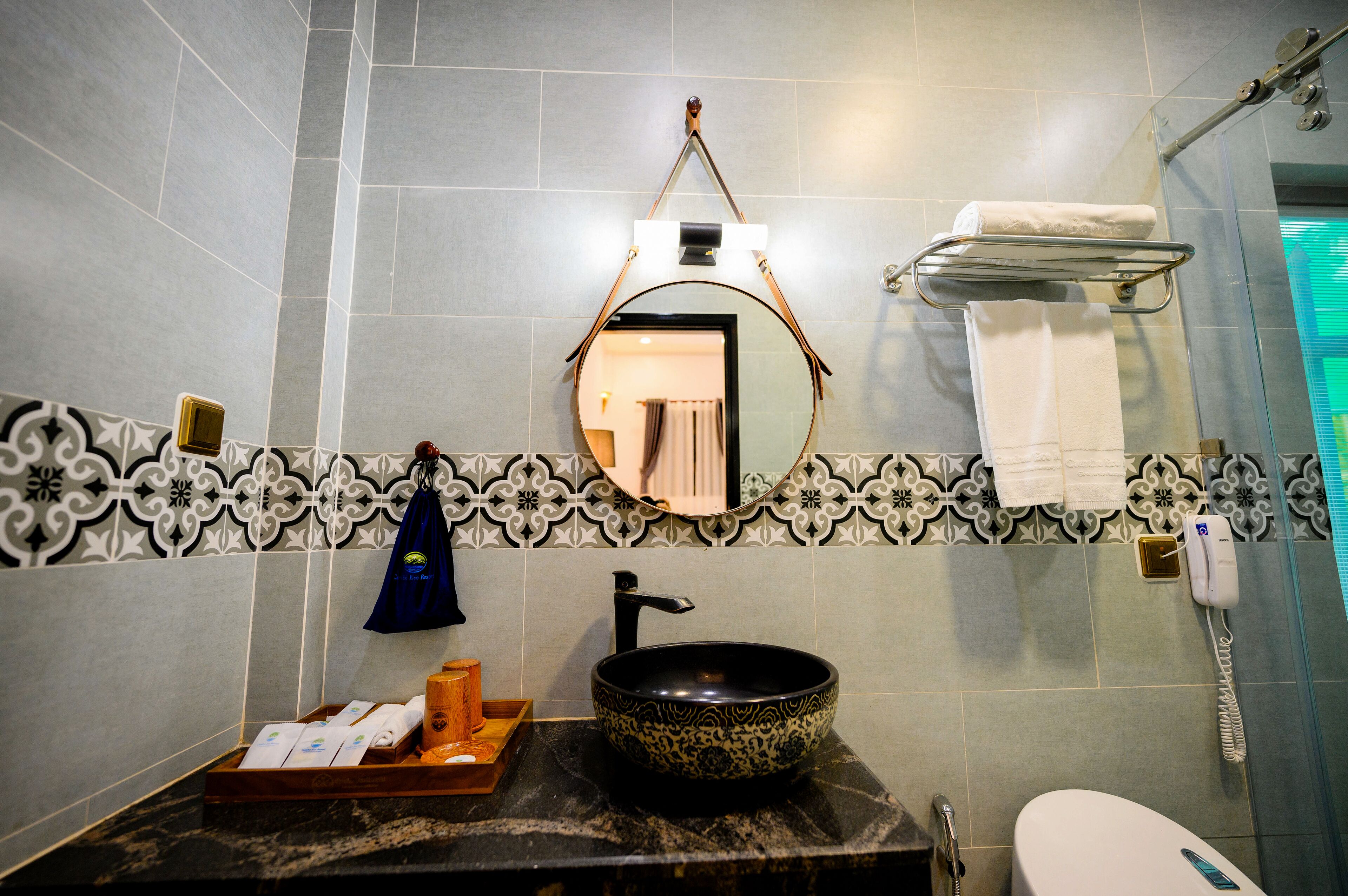Un bany amb un lavabo rodó, un mirall, un suport per tovalloles i una dutxa.