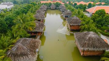 A waterway lined with thatched-roof huts, surrounded by lush greenery.