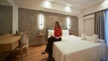 Une chambre d’hôtel comprenant un lit, une table de chevet, une lampe et un bureau avec une chaise.