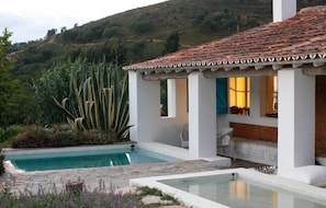 A pool with a white exterior, a patio area with a white chair, and a view of a hilly landscape. - Herdade DA Matinha Country House Restaurant (Santiago do Cacém)