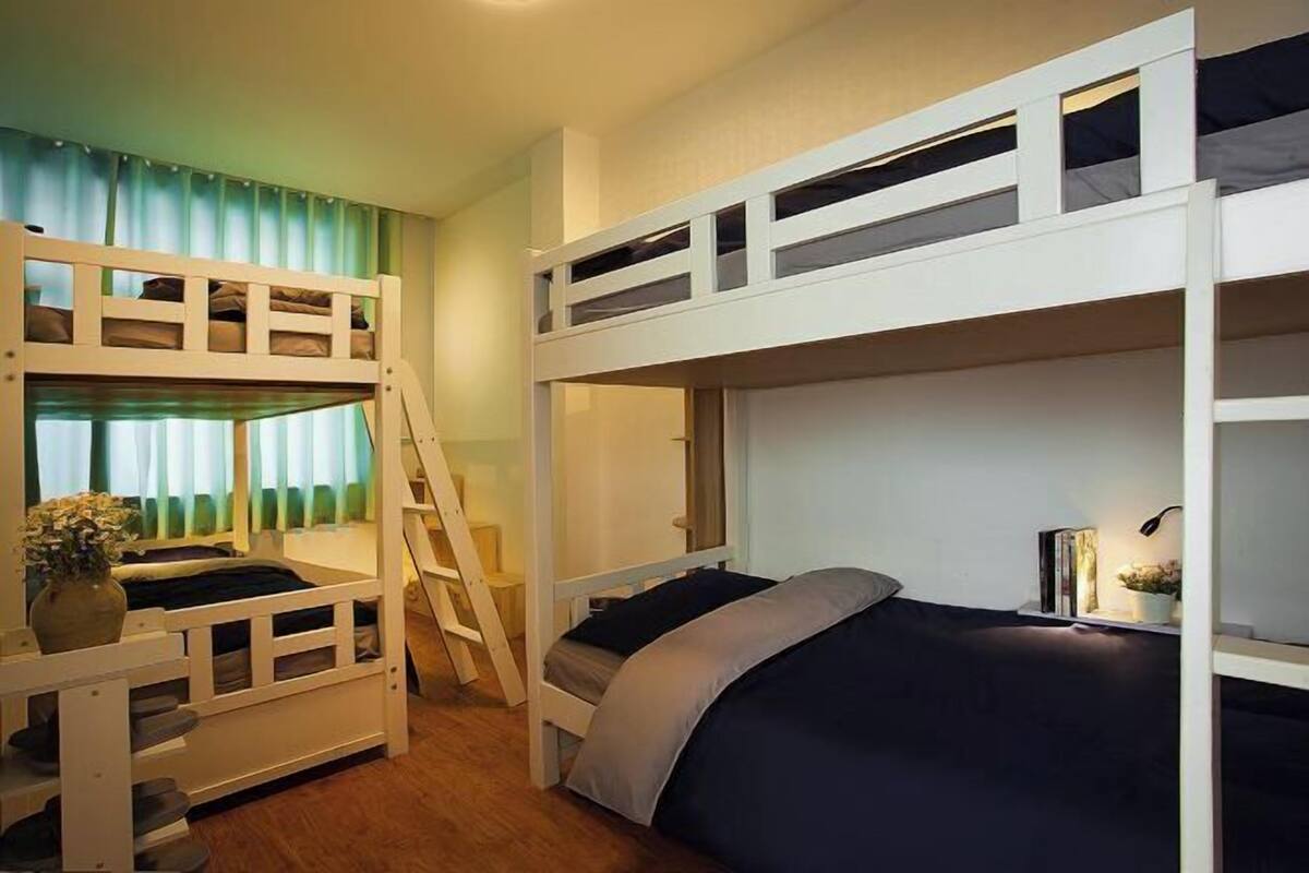 A bunk bed room with a ladder, a desk, and a chair.