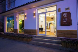A building with a large glass door entrance, a sign with Chinese characters, and a wooden bench outside. - Dali Ancient Town No. 204 Ideal Youth Hostel (Dali City)