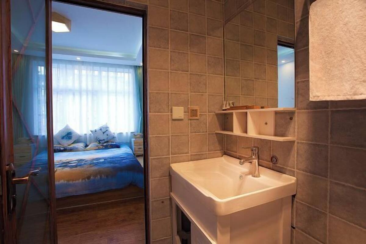 A hotel room with a bed, a bathroom with a sink, and a mirror.