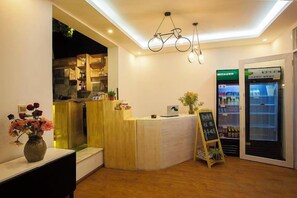 Un espace d’accueil comprenant un comptoir, un réfrigérateur et un tableau noir servant de menu.
