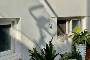 A building exterior with a window, a wall-mounted light fixture, and potted plants. - Dali Ancient Town No. 204 Ideal Youth Hostel (Dali City)
