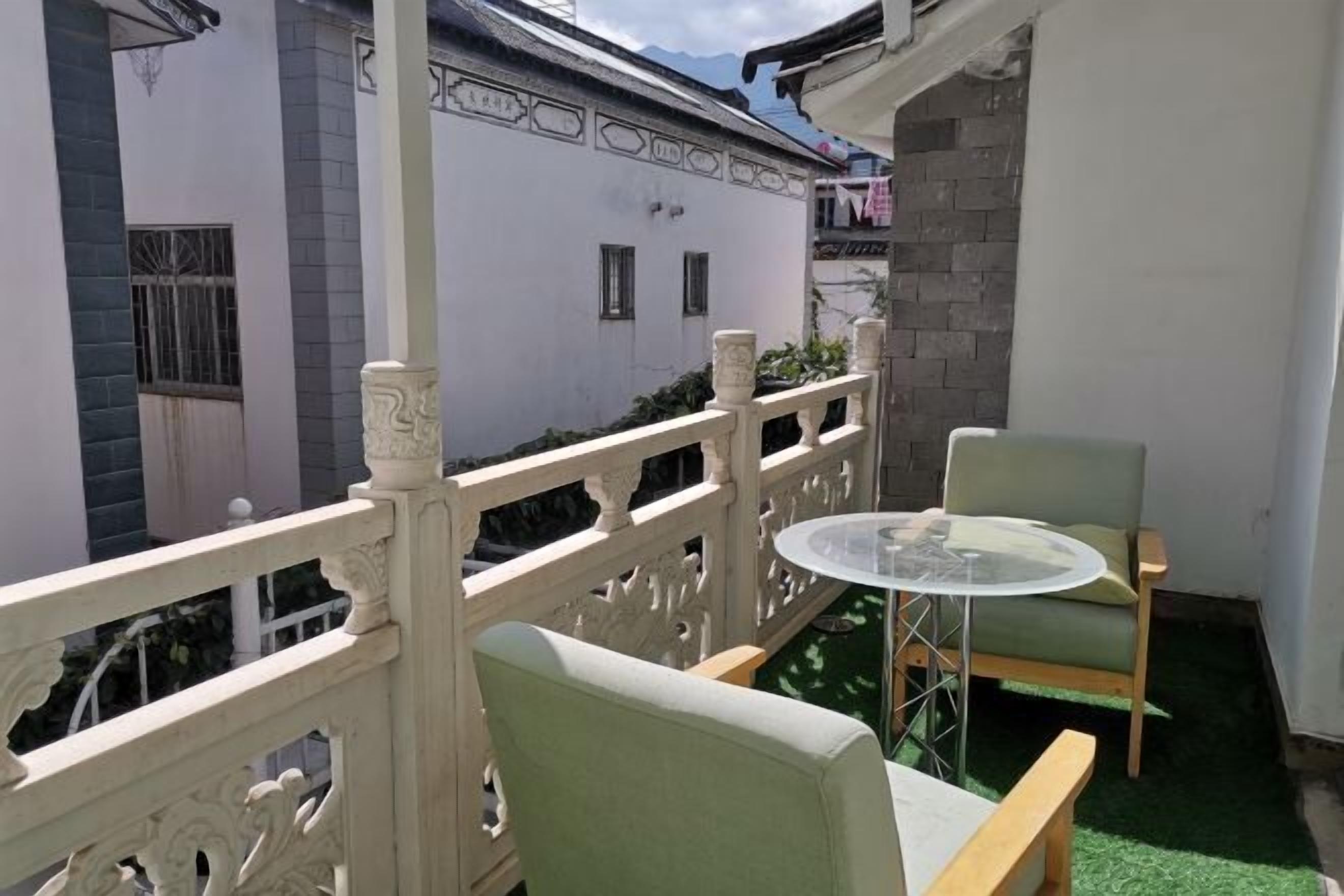 Un balcon avec une balustrade blanche, une table ronde et deux chaises.