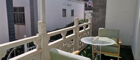 A balcony with a white railing, a round table, and two chairs.