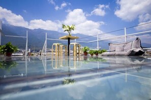 A modern indoor pool area with clear glass flooring, a seating area with a sofa and chairs, and a potted plant. - Dali Ancient Town No. 204 Ideal Youth Hostel (Dali City)