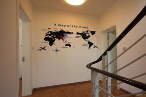 A hallway with a world map mural on the wall, a staircase, and wooden flooring. - Dali Ancient Town No. 204 Ideal Youth Hostel (Dali City)