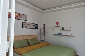 A bedroom with a bed, green and yellow bedding, a wooden headboard, and wall-mounted shelves with decorative items. - Dali Ancient Town No. 204 Ideal Youth Hostel (Dali City)