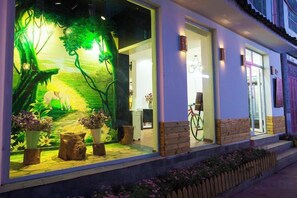 A hotel entrance with a large illuminated mural, a bicycle outside, and a well-maintained exterior. - Dali Ancient Town No. 204 Ideal Youth Hostel (Dali City)
